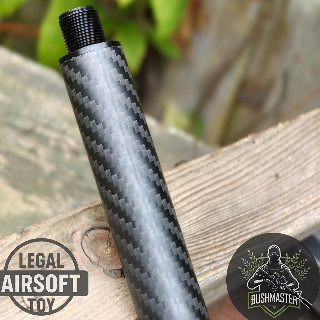 Close-up of carbon fiber airsoft suppressor placed on wooden surface with Legal Airsoft Toy and Bushmaster logos