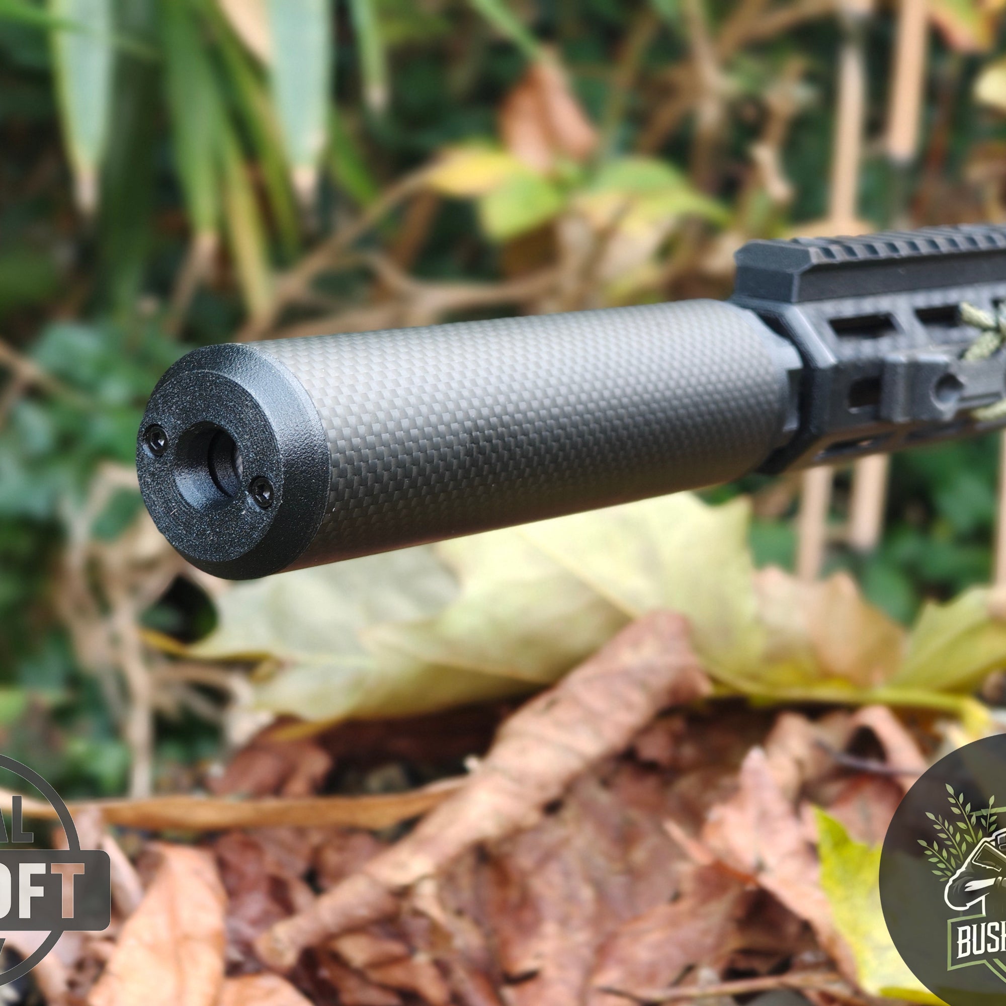 Close-up of carbon fiber suppressor attached to black tactical rifle in outdoor autumn setting