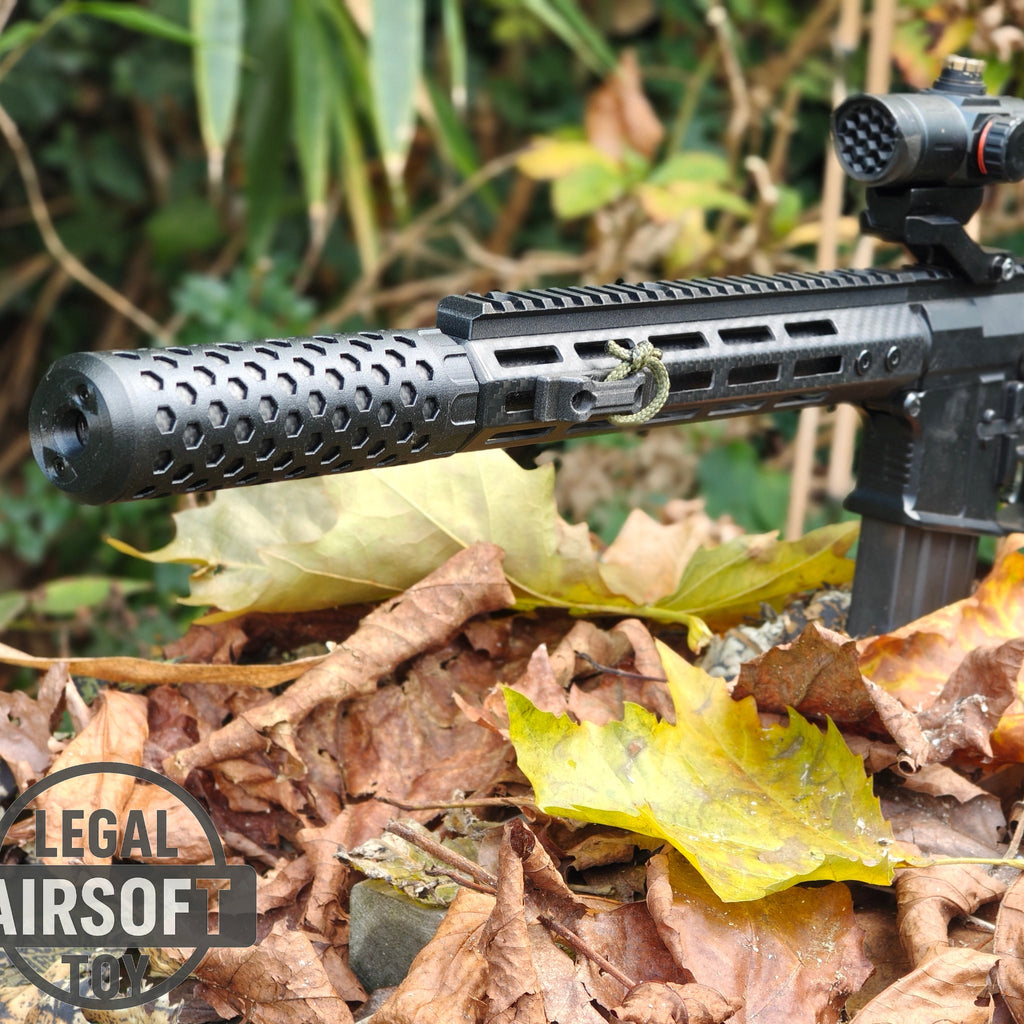 Close-up of black airsoft rifle with silencer and scope on dry leaves outdoors
