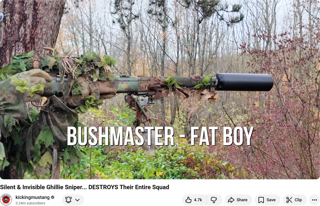 Sniper in ghillie suit aiming Bushmaster Fat Boy rifle with suppressor in forest