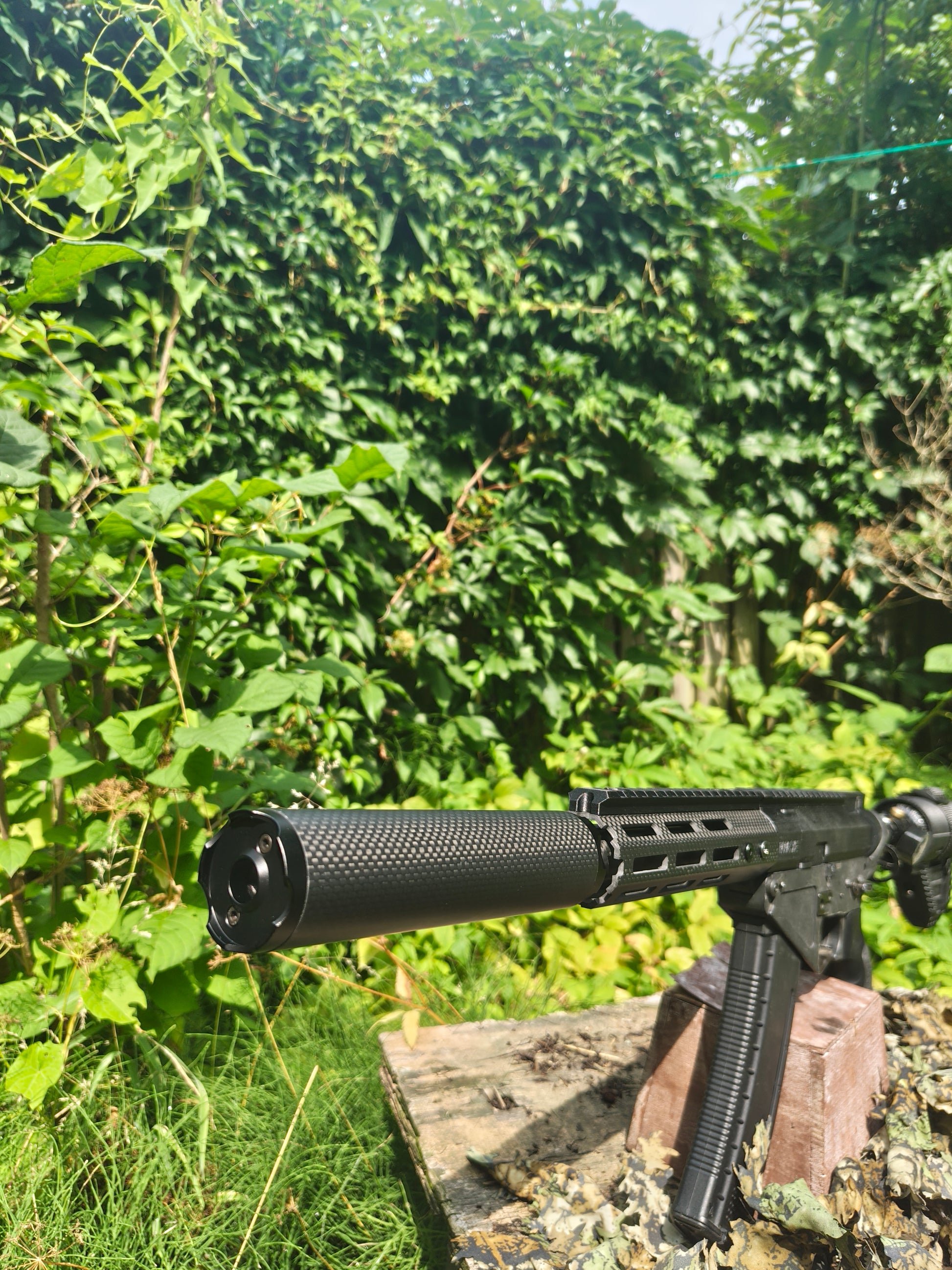 Wide outdoor view of an airsoft replica fitted with the Bushmaster Model Core sound moderator