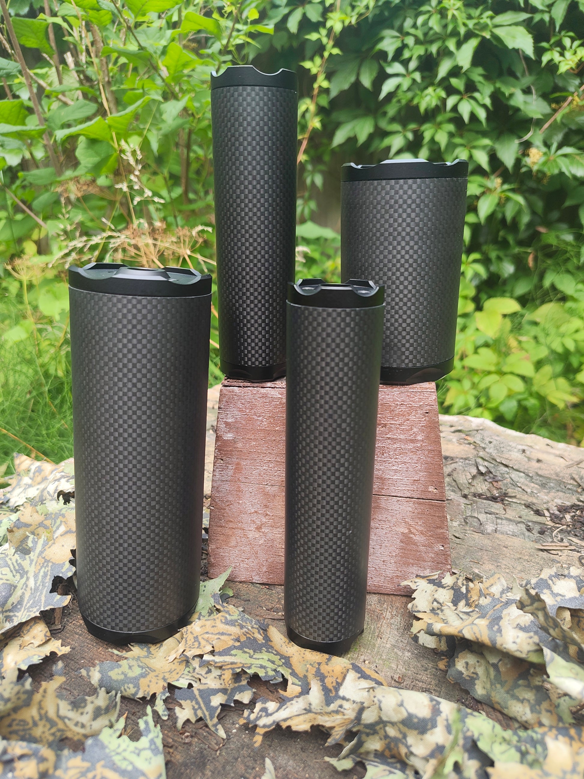 Four Bushmaster Model Core carbon-fiber sound moderators in different lengths displayed outdoors