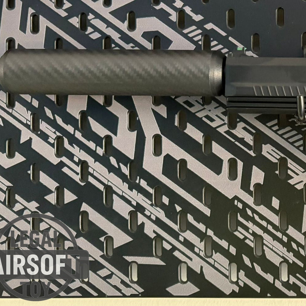 Close-up of black airsoft pistol with silencer on patterned black and gray surface