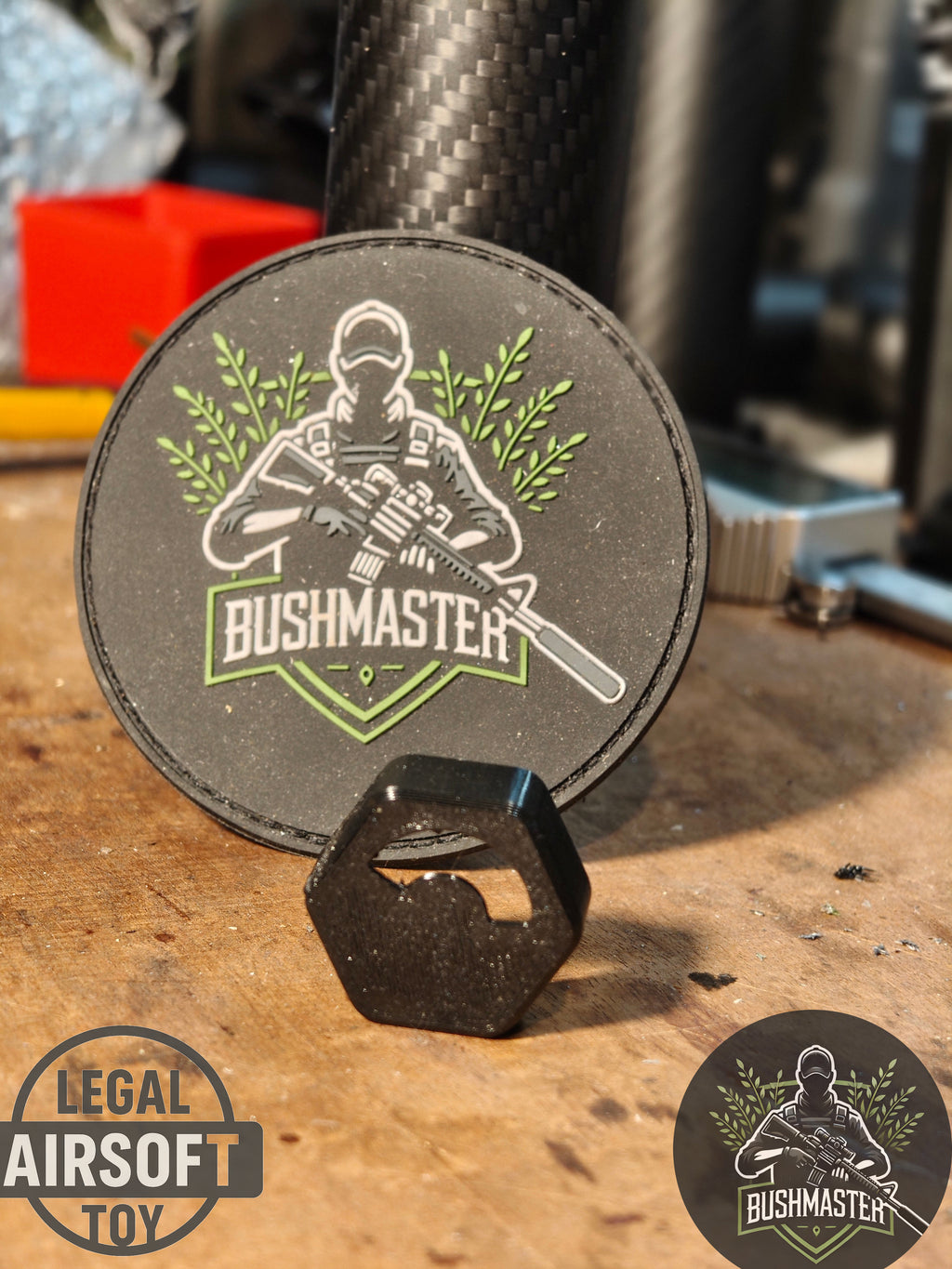 Bushmaster patch with soldier holding rifle, green foliage, placed on wooden surface with carbon fiber background
